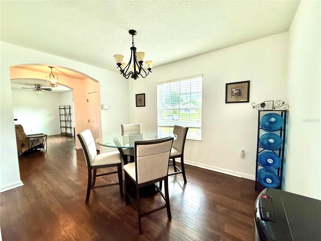 A dining room features a glass table, four chairs, a chandelier, and wood flooring — 331 ALDER AVENUE SE, PALM BAY, FL