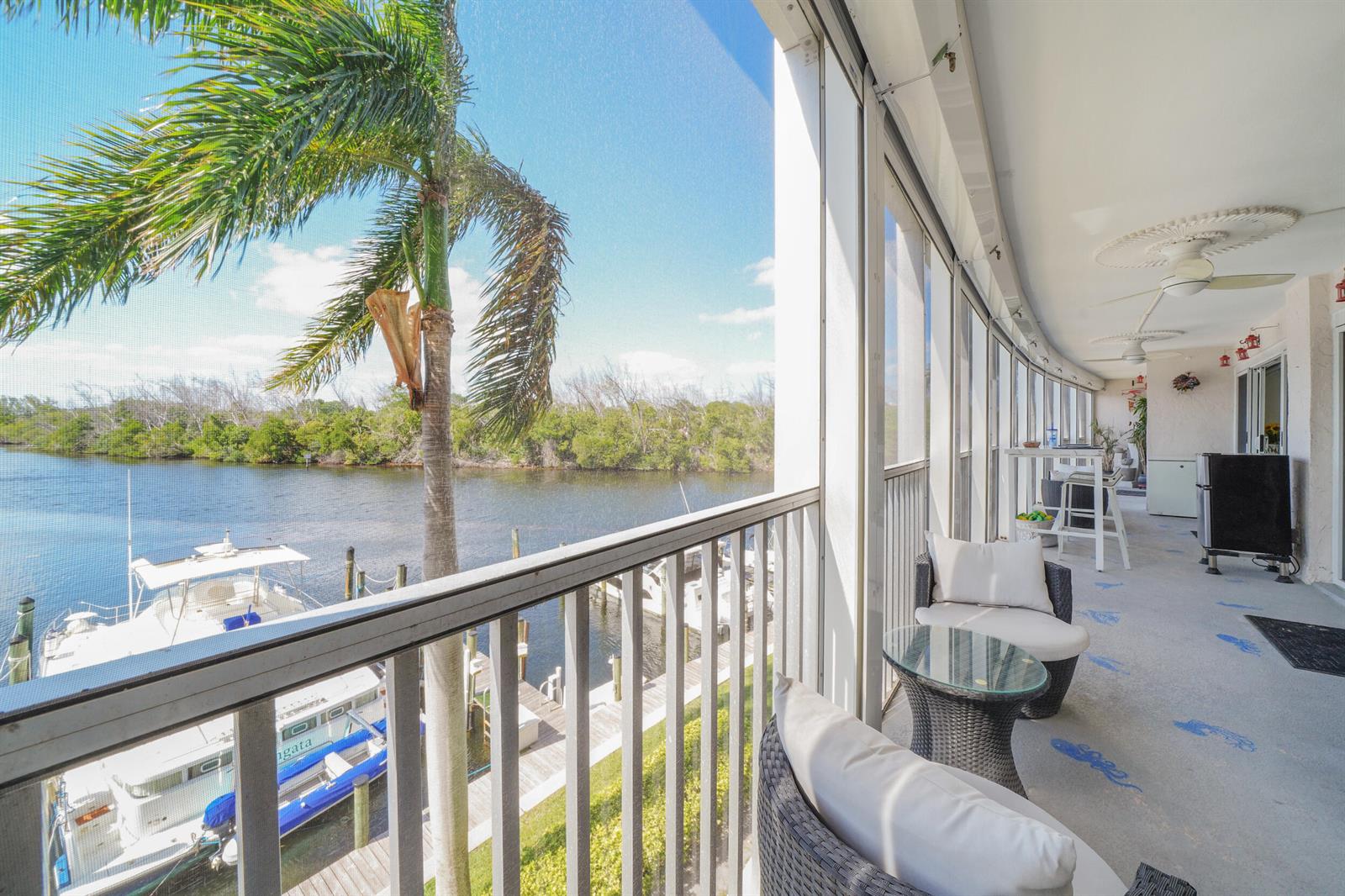 A screened-in balcony overlooks a canal with a boat dock and a palm tree — 1537 E Hillsboro Boulevard # 341, Deerfield Beach FL 33441, DEERFIELD BEACH, FL
