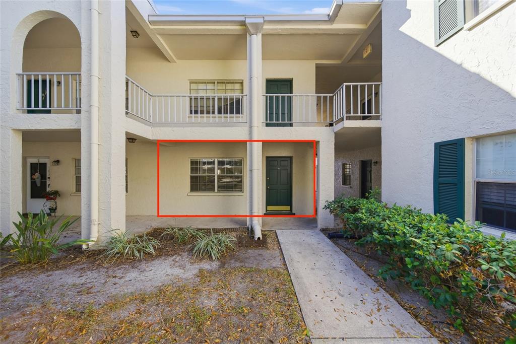 A ground-level apartment entrance with a green door and window under a covered walkway — 4335 AEGEAN DRIVE UNIT 144A, TAMPA, FL