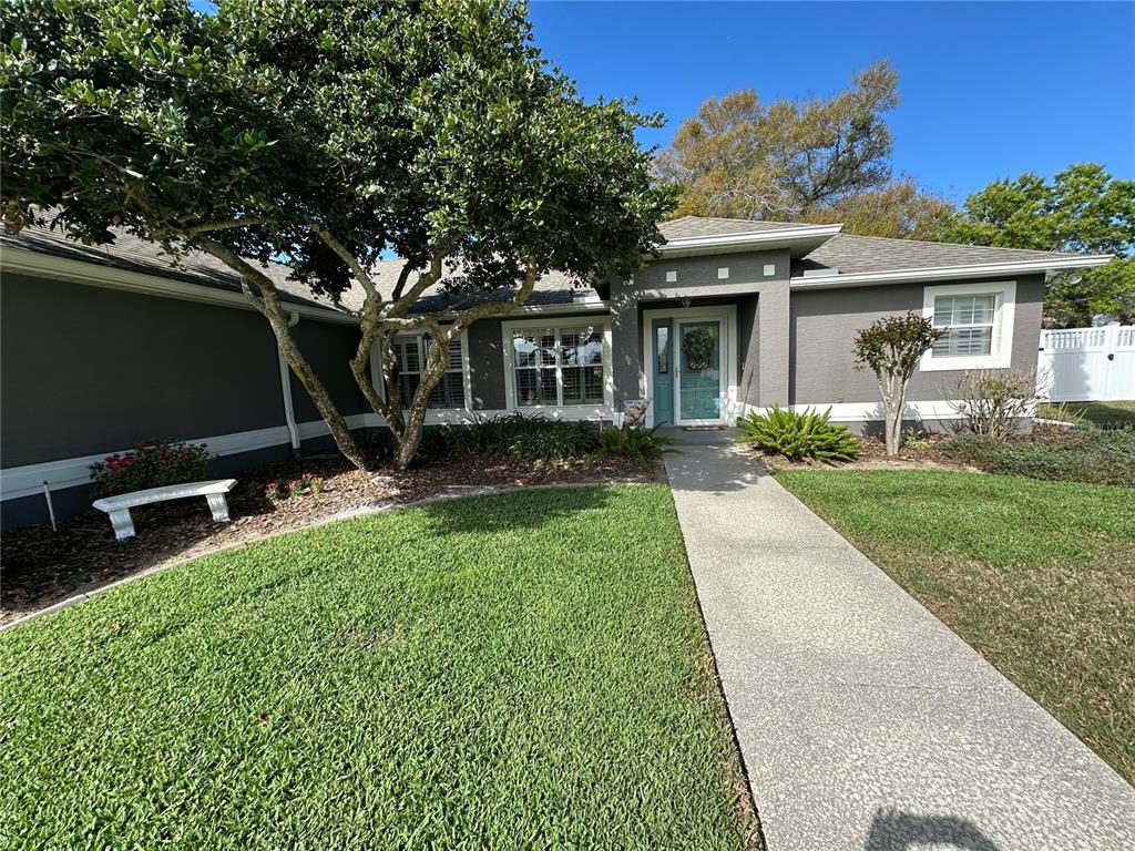 A gray single-story house features a concrete walkway leading to a light blue front door — 417 ANDERSON DRIVE, TAVARES, FL