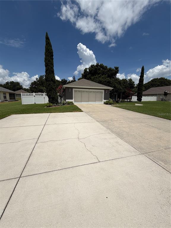 A concrete driveway leads to a detached three-car garage under a blue sky — 417 ANDERSON DRIVE, TAVARES, FL