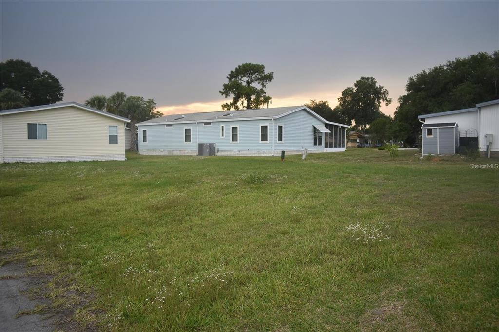 A light blue manufactured home sits on a grassy lot next to a yellow house — LOT 8 BLK C LIBERTY COURT, WILDWOOD, FL