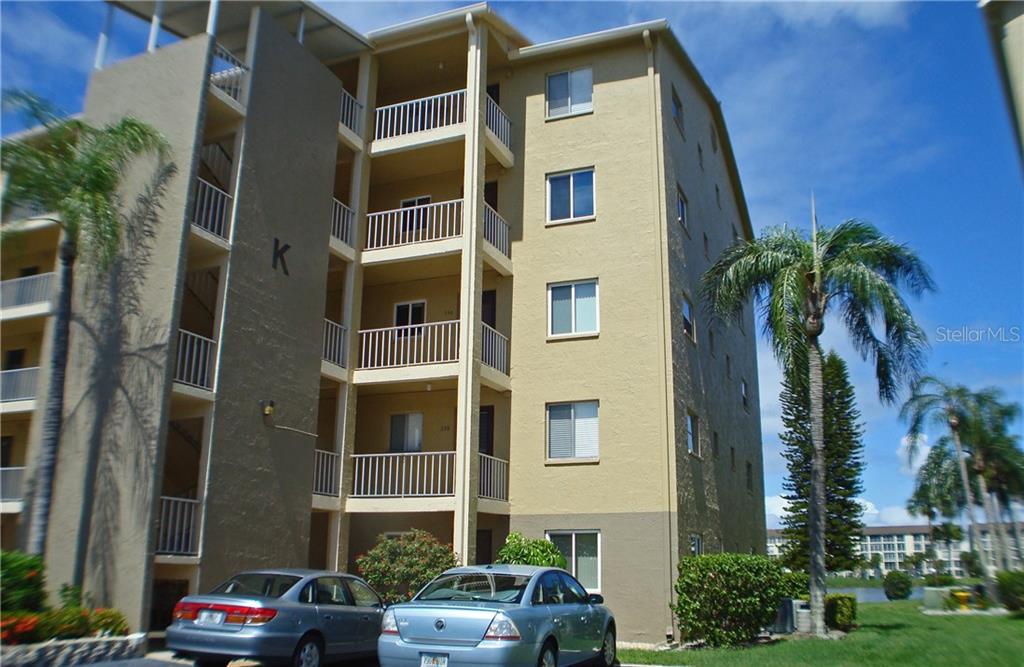 A multi-story apartment building with a beige exterior, balconies, and parked cars in front — 3668 LAKE BAYSHORE DRIVE UNIT K-325, BRADENTON, FL