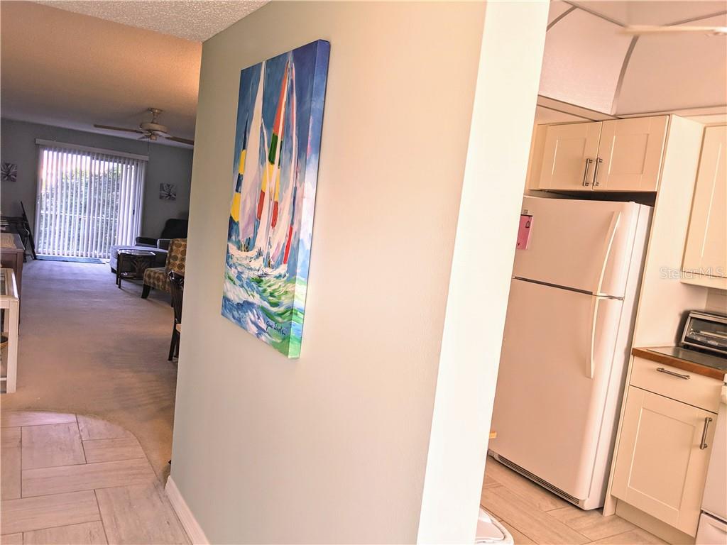 A view from a tiled kitchen looking toward a living area with a sailboat painting — 3668 LAKE BAYSHORE DRIVE UNIT K-325, BRADENTON, FL
