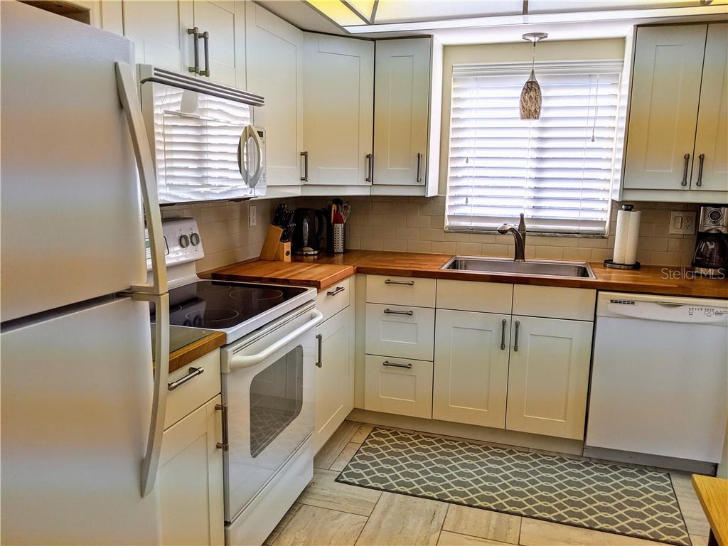 A kitchen features white cabinets, wood countertops, a white stove, and a stainless steel sink — 3668 LAKE BAYSHORE DRIVE UNIT K-325, BRADENTON, FL