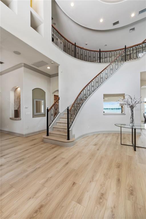 A grand foyer features light wood flooring, a curved staircase, and a circular ceiling design — 7926 VERSILIA DRIVE, ORLANDO, FL
