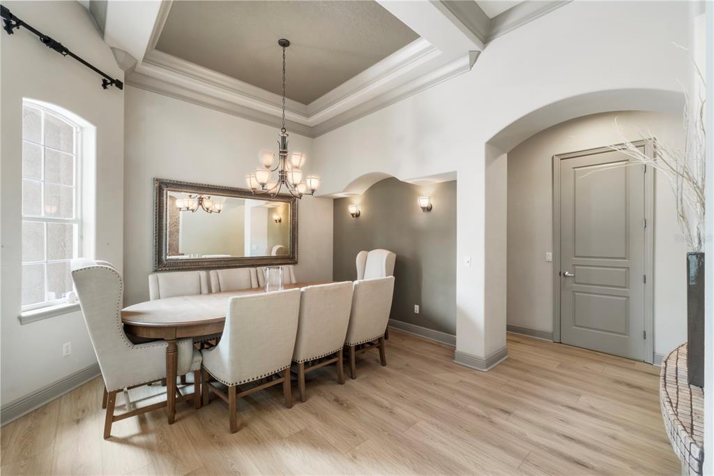 A dining room features a tray ceiling, a chandelier, a long table, and upholstered chairs — 7926 VERSILIA DRIVE, ORLANDO, FL
