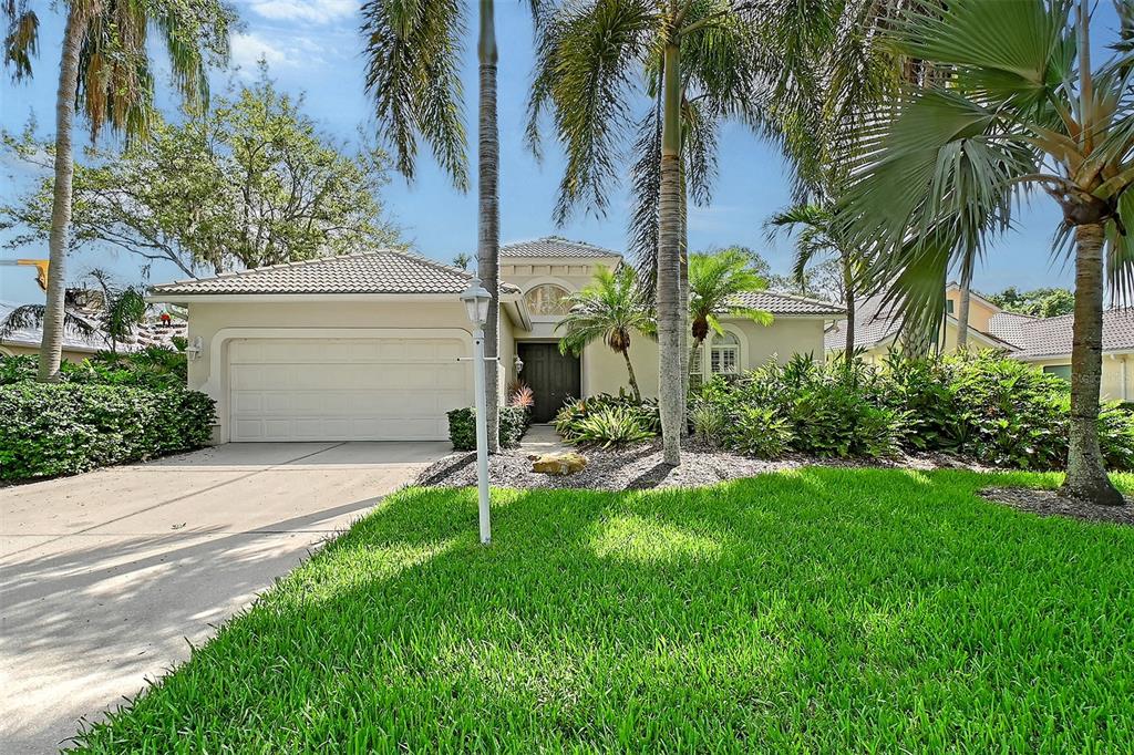 A single-story house with a two-car garage, palm trees, and a landscaped front yard — 5839 LOS VERDES COURT, BRADENTON, FL