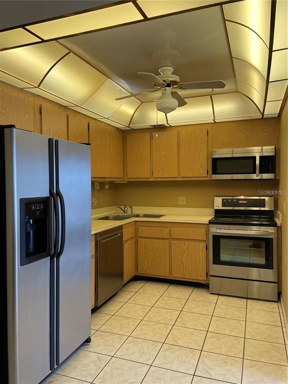 A kitchen features light wood cabinets, stainless steel appliances, and a recessed tray ceiling — 830 S GULFVIEW BOULEVARD UNIT 601, CLEARWATER BEACH, FL