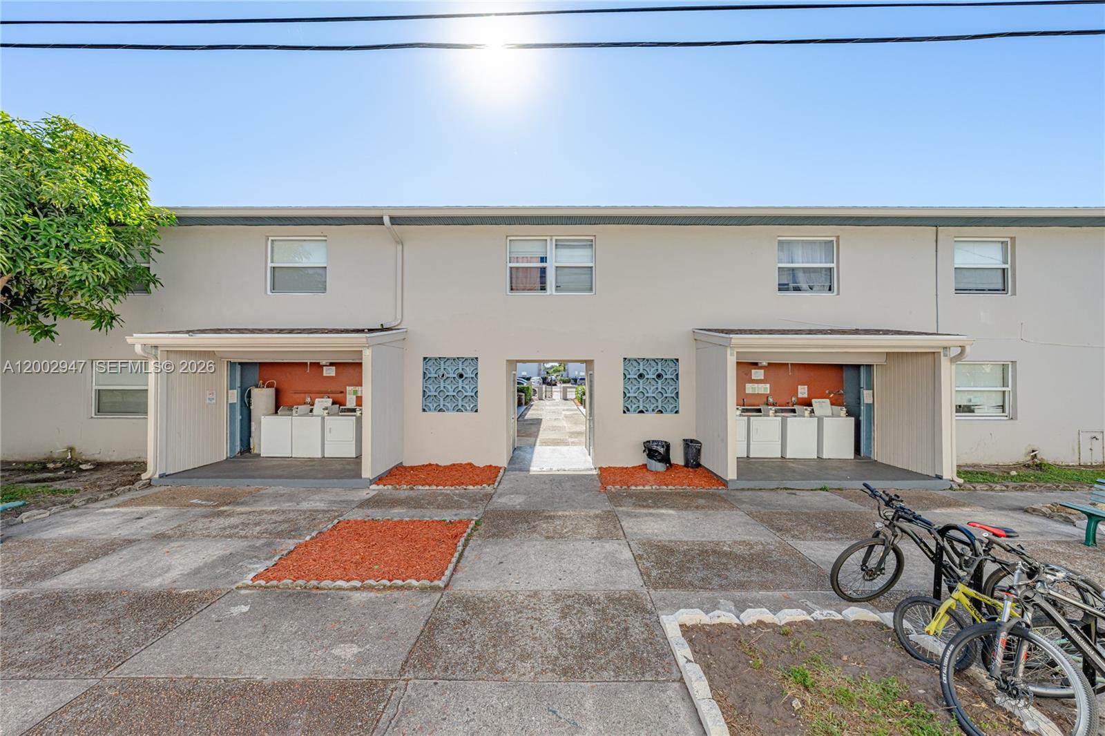 The exterior of a two-story apartment building features two open-air laundry areas on the ground floor — 939 Magnolia DRIVE # L, Lake Park FL 33403, LAKE PARK, FL