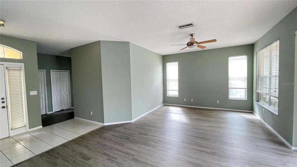 An empty living room features light green walls, wood-look flooring, and a ceiling fan — 210 41ST STREET NE, BRADENTON, FL