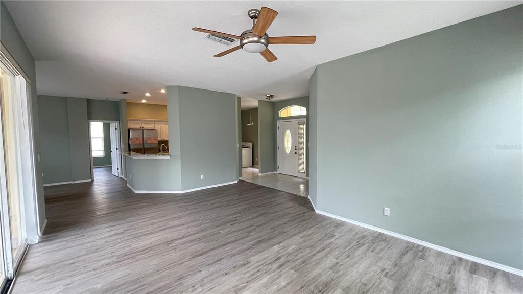 An open-concept living area features light green walls, wood-look flooring, and a ceiling fan — 210 41ST STREET NE, BRADENTON, FL