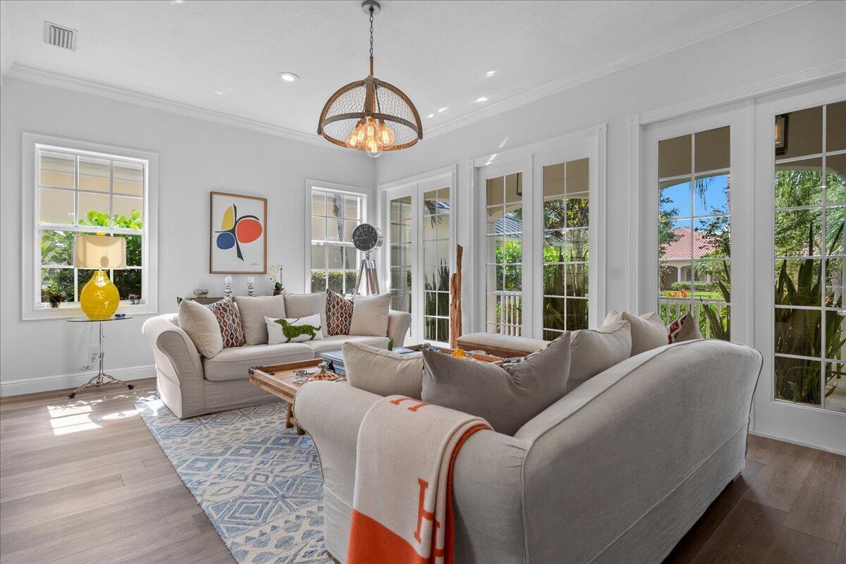 A bright living room features two beige sofas, a patterned rug, and glass patio doors — 8465 Belize Place, Wellington FL 33414, WELLINGTON, FL