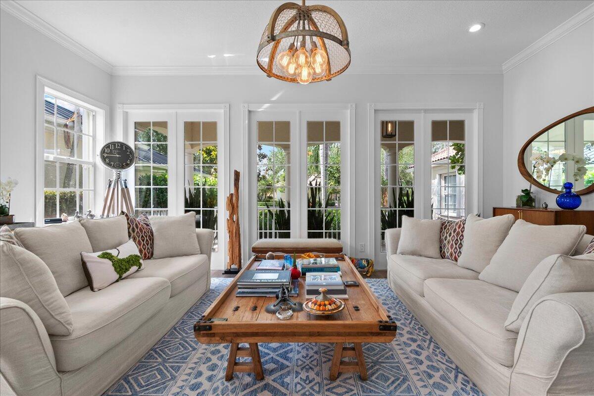 A living room features two beige sofas, a wooden coffee table, and a rustic chandelier — 8465 Belize Place, Wellington FL 33414, WELLINGTON, FL