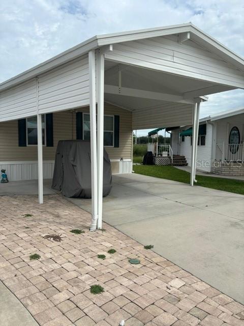 A covered carport with a paved driveway and a golf cart parked underneath — 9000 US HWY 192 UNIT 56, CLERMONT, FL