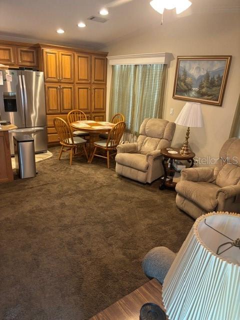 A kitchen and living area feature wood cabinetry, a round dining table, and two recliners — 9000 US HWY 192 UNIT 56, CLERMONT, FL
