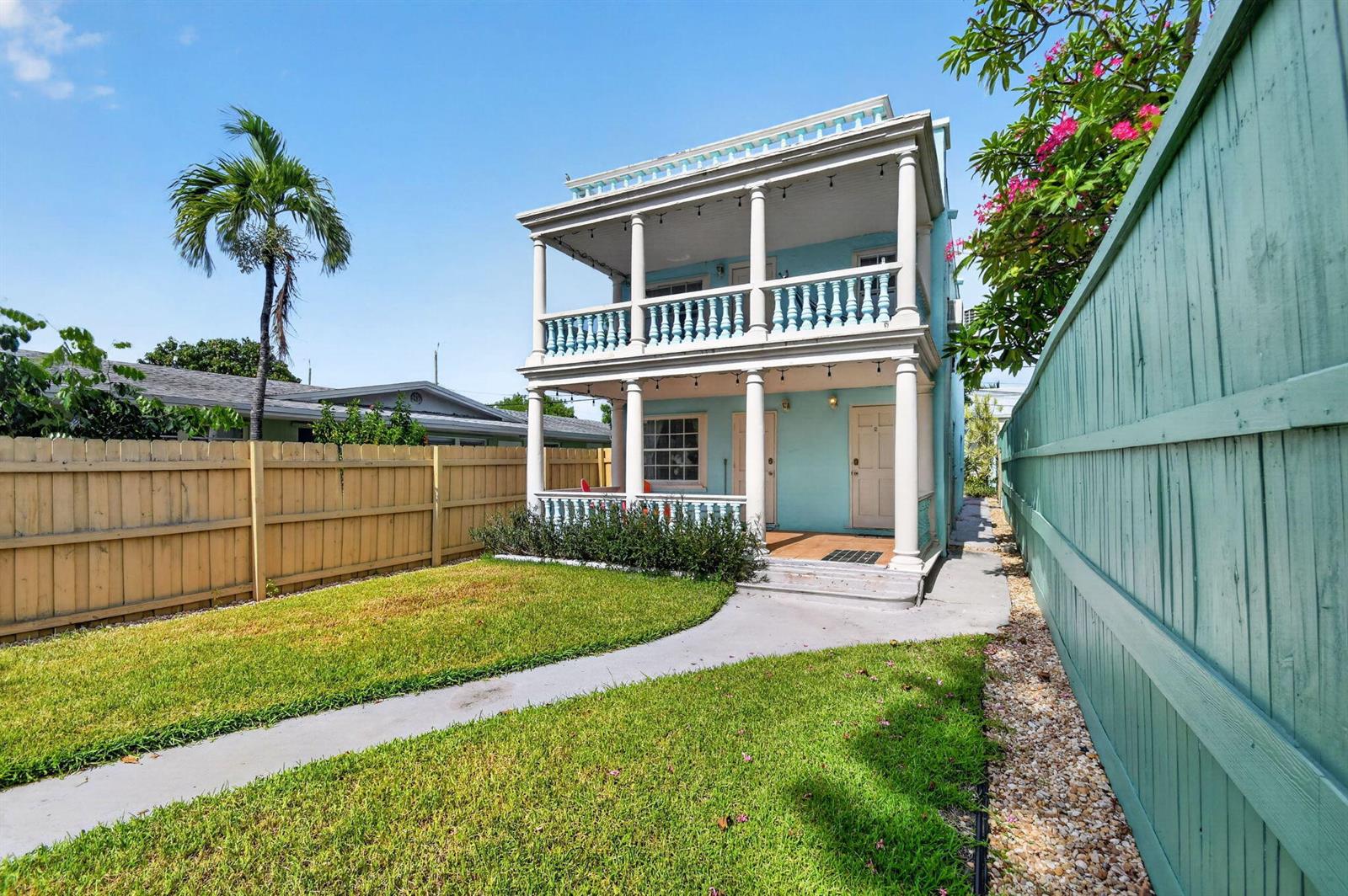 A two-story light blue house with a double-decker porch stands behind a grassy yard — 508 N K Street # 1, FL 33460, FL