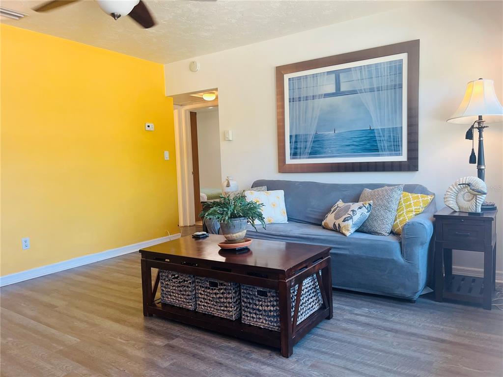 A living room features a yellow accent wall, a blue sofa, and a wooden coffee table — 551 ORANGEWOOD DRIVE, DUNEDIN, FL