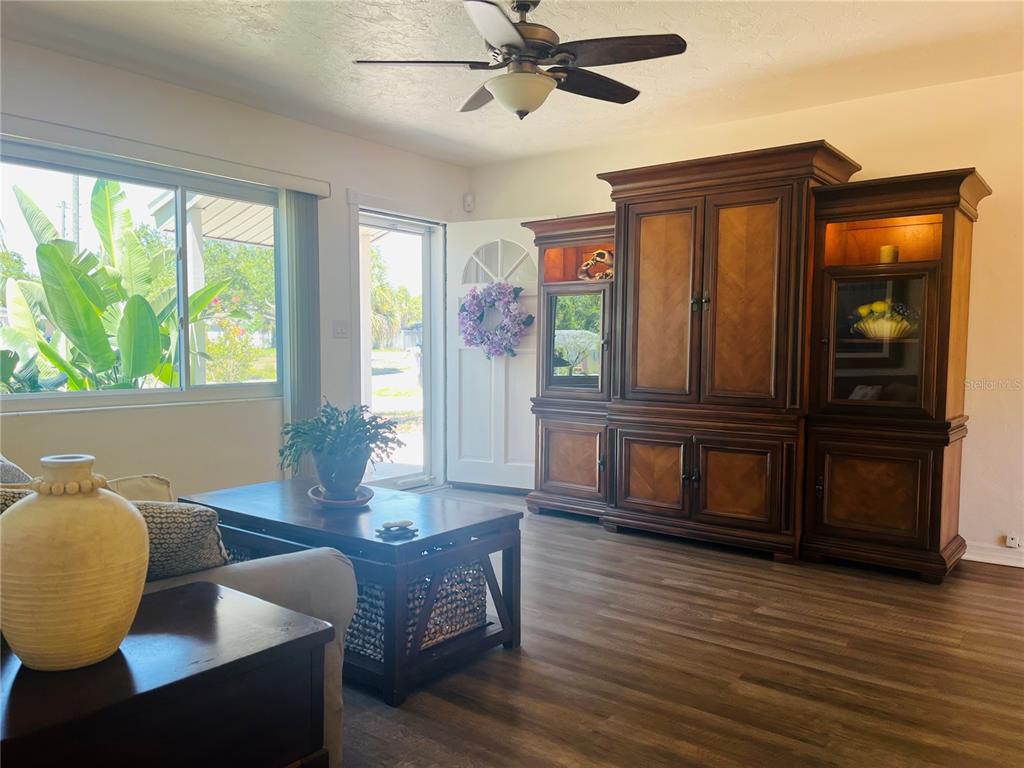 A living room features wood-look flooring, a large wooden entertainment center, and a ceiling fan — 551 ORANGEWOOD DRIVE, DUNEDIN, FL