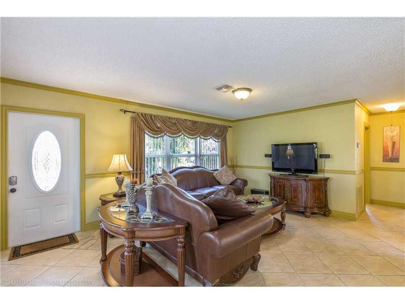 A living room features yellow walls, tile flooring, a leather sofa, and a television console — 160 SE 12th Street, Pompano Beach FL 33060, POMPANO BEACH, FL