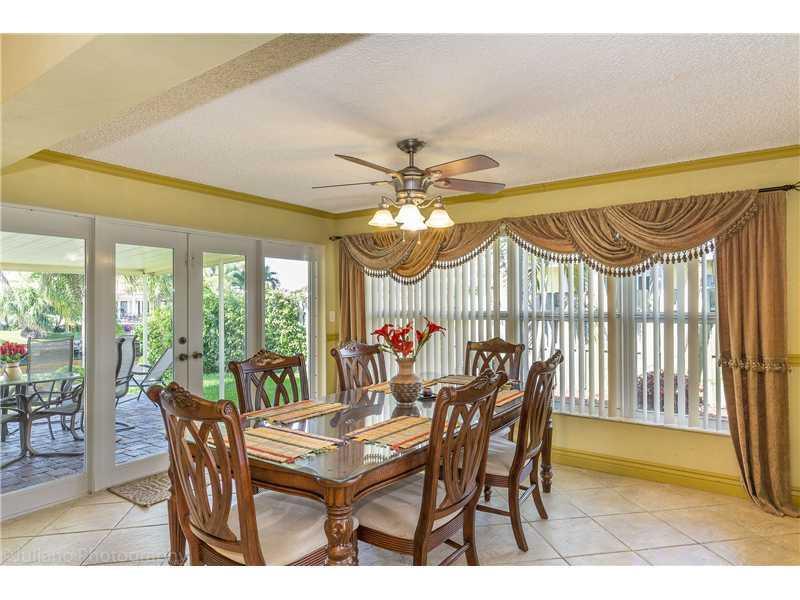 A dining room with a glass-topped table, wooden chairs, ceiling fan, and large sliding doors — 160 SE 12th Street, Pompano Beach FL 33060, POMPANO BEACH, FL