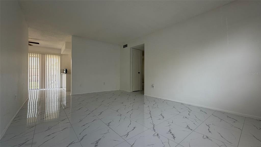 An empty room features white walls and glossy white tile flooring with grey veining — 5325 CURRY FORD ROAD UNIT D206, ORLANDO, FL