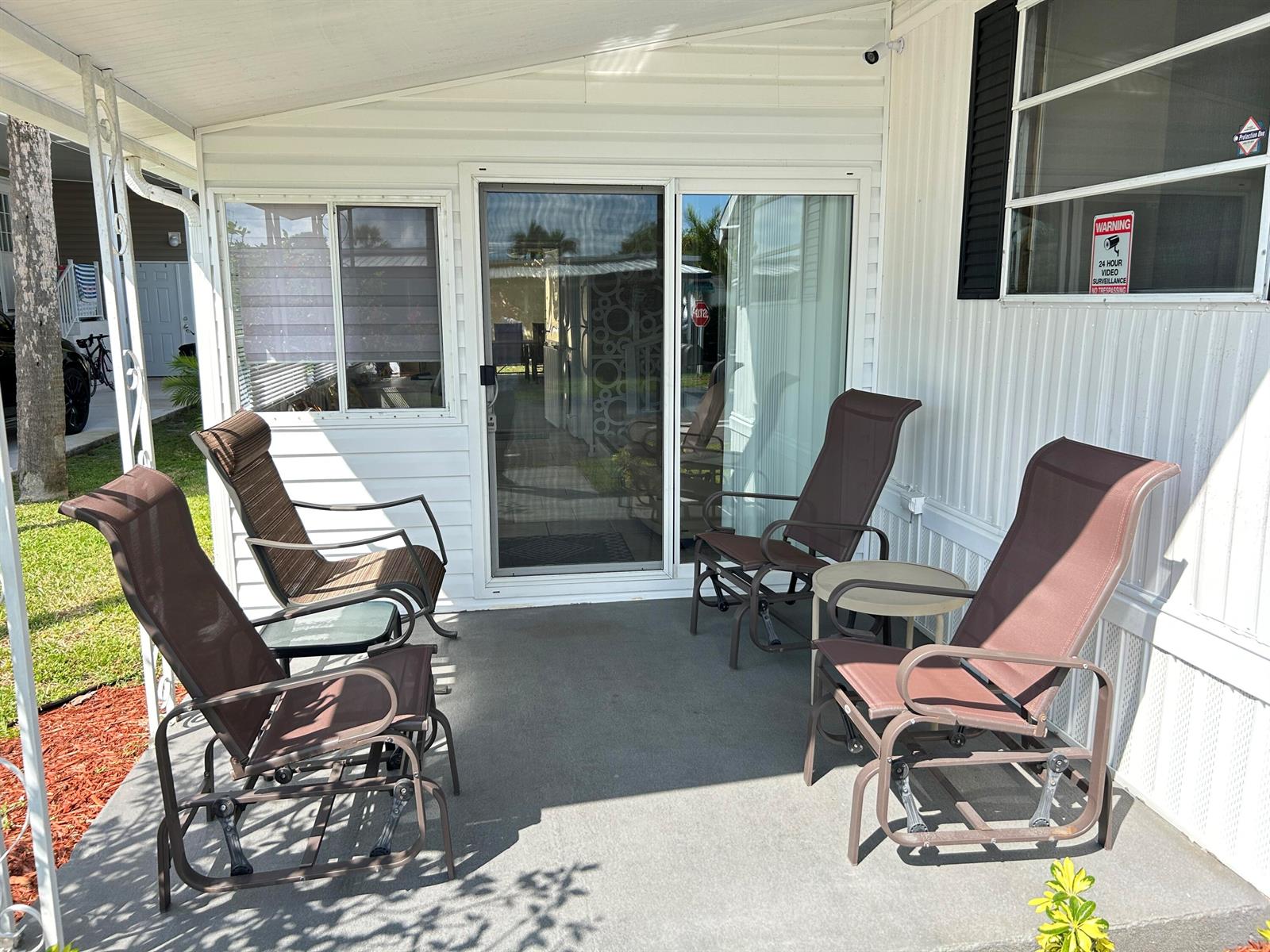 A covered patio features four brown outdoor chairs and two small tables outside a sliding door — 615 Alamanda Lane, Deerfield Beach FL 33442, DEERFIELD BEACH, FL