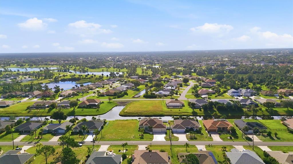 An aerial view of a suburban neighborhood featuring houses, a canal, and a vacant lot — 90 BROADMOOR LANE, ROTONDA WEST, FL