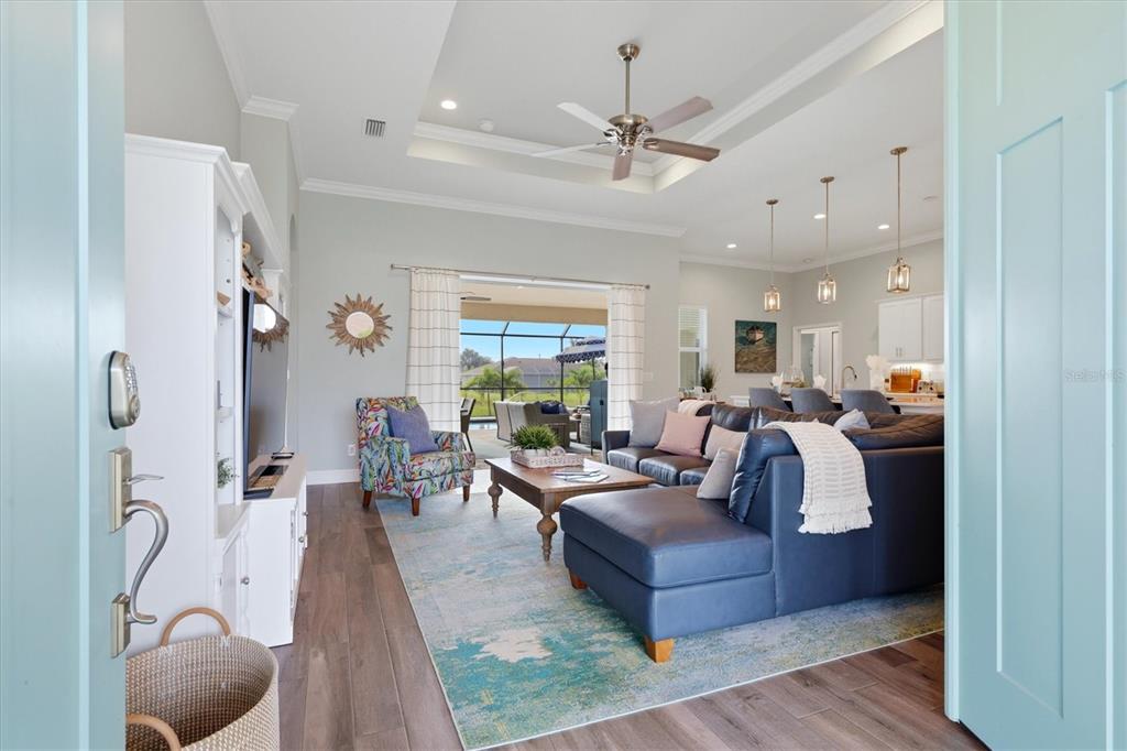 A living room with a blue sectional, patterned armchair, and a view of a pool — 90 BROADMOOR LANE, ROTONDA WEST, FL