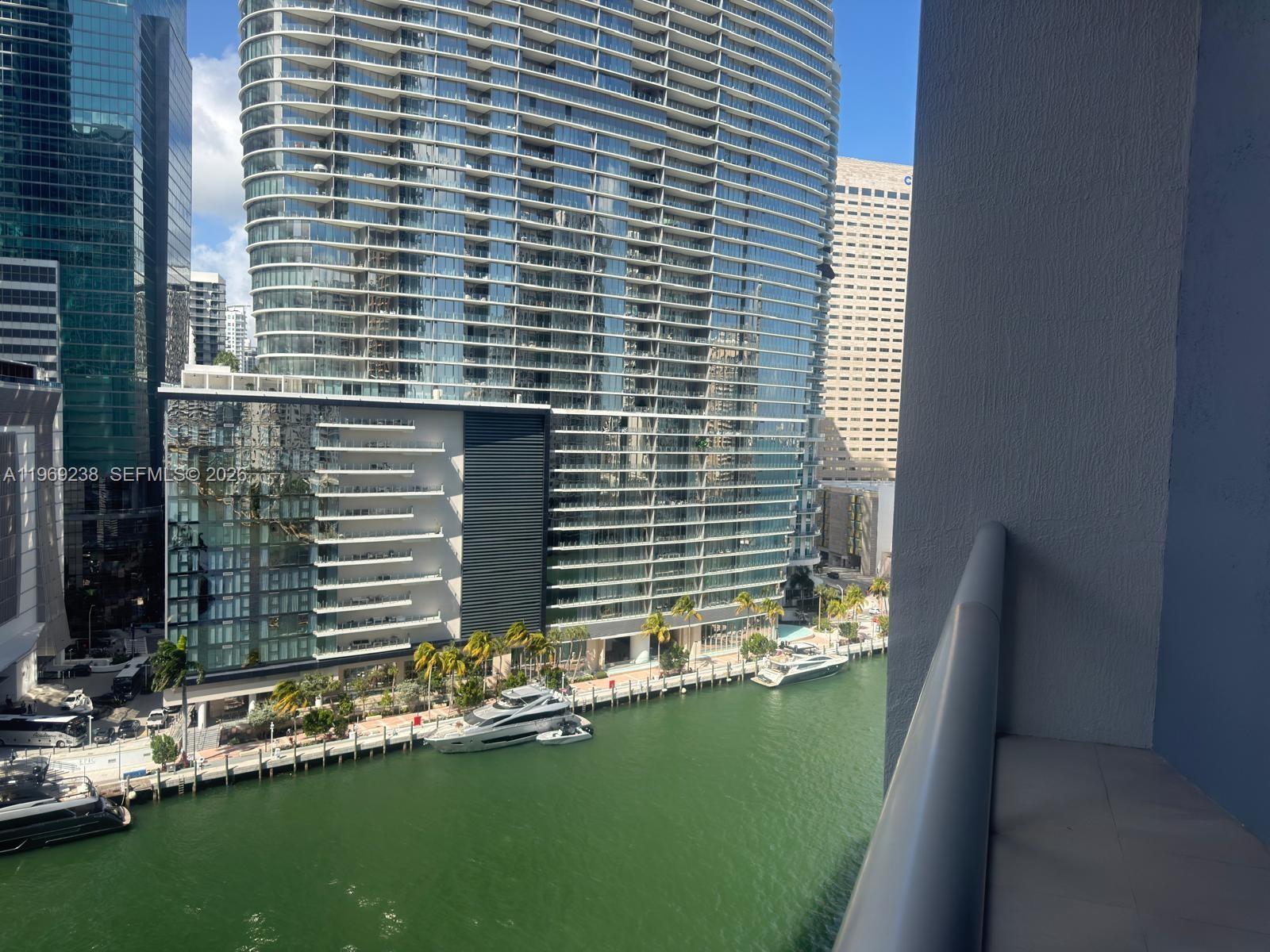 A balcony view overlooks a canal with docked yachts and modern high-rise buildings — 465 Brickell # 1504, Miami FL 33131, MIAMI, FL