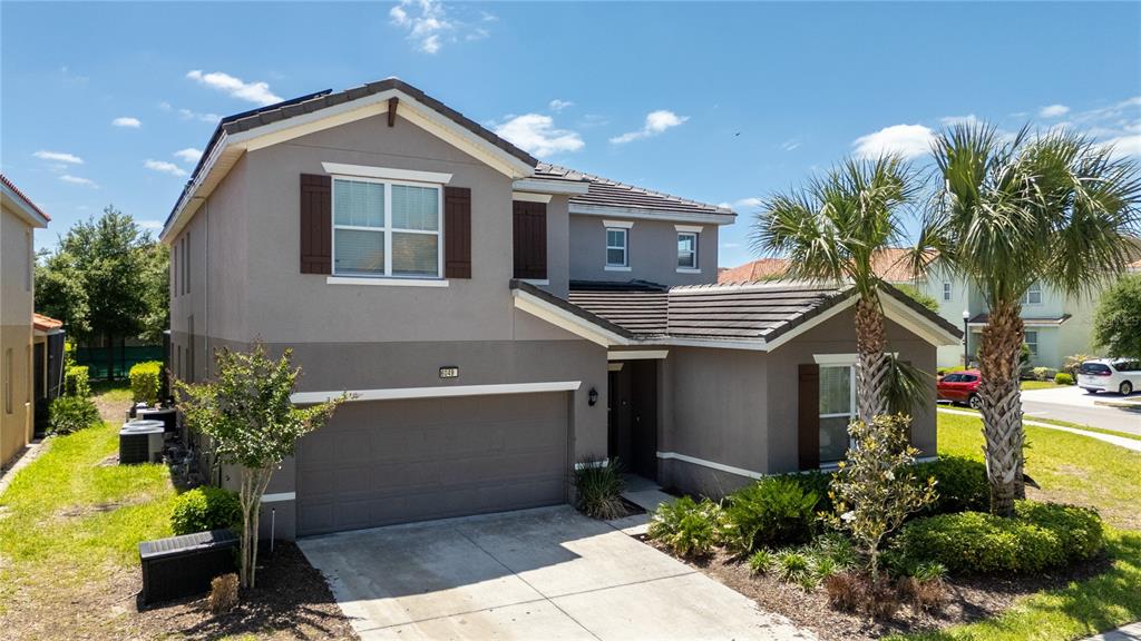 A two-story house with a gray exterior, a two-car garage, and a palm tree — 6049 BROAD OAK DRIVE, DAVENPORT, FL