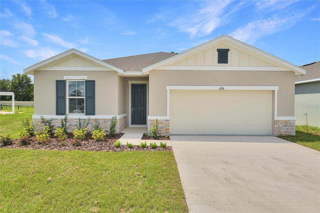 A single-story house features a beige stucco exterior, stone accents, and a two-car garage — 6196 SW 64TH TERRACE, OCALA, FL