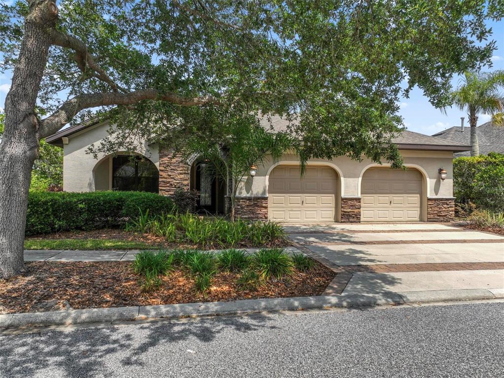 A single-story house with a two-car garage, stone accents, and a large tree in front — 5 SANDPIPER COURT, PALM COAST, FL