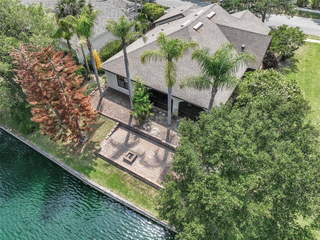 An aerial view of a house with a paver patio, fire pit, and waterfront backyard — 5 SANDPIPER COURT, PALM COAST, FL