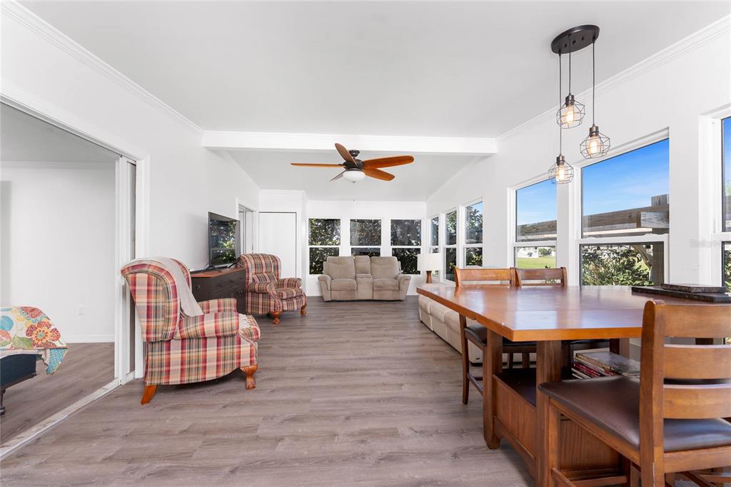 A bright sunroom features wood-look flooring, a dining set, and a living area with furniture — 7548 RATAN CIRCLE, PORT CHARLOTTE, FL