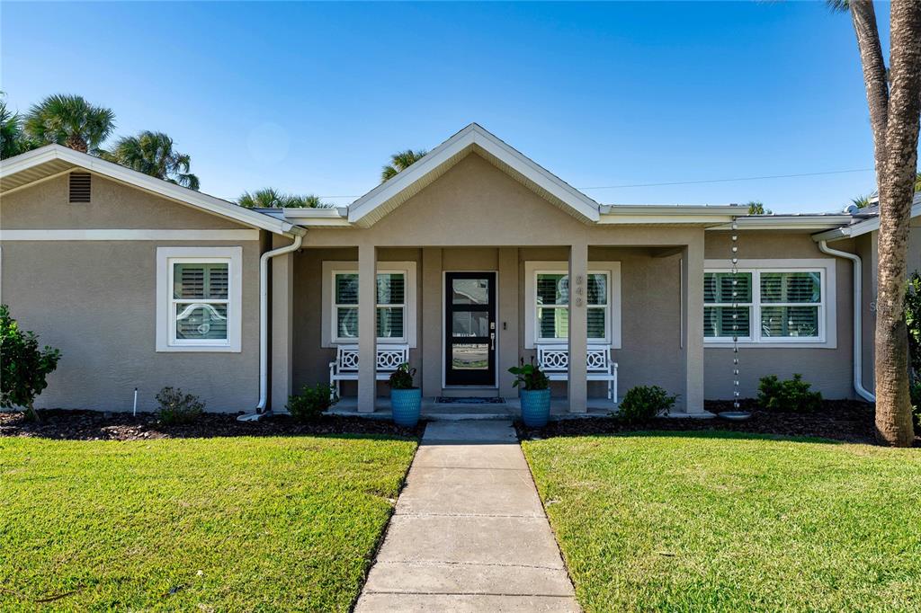 A single-story house with a beige stucco exterior, a covered porch, and a concrete walkway — 848 MANDALAY AVENUE, CLEARWATER BEACH, FL