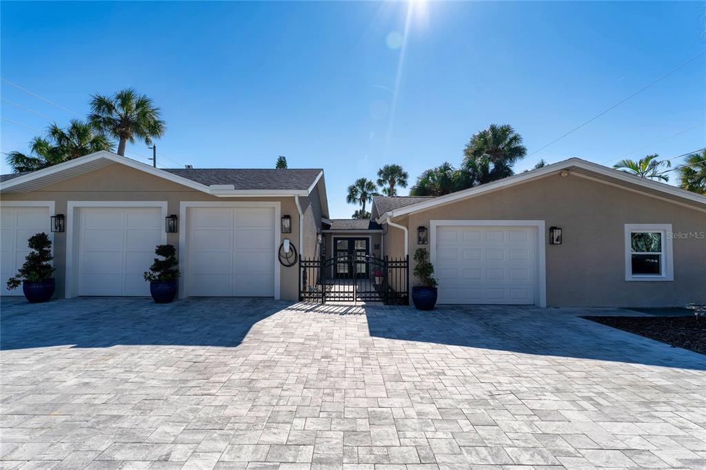 A paved driveway leads to a house with three garage doors and a central gate — 848 MANDALAY AVENUE, CLEARWATER BEACH, FL