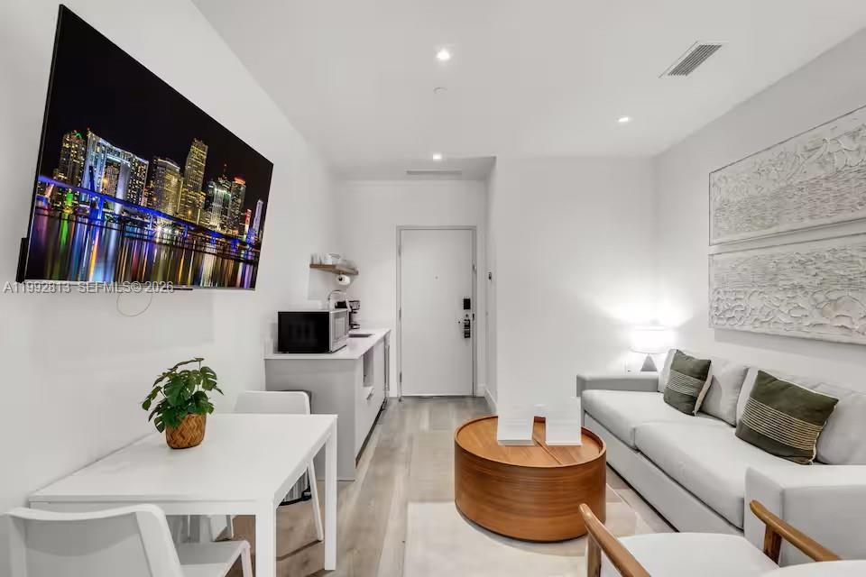 A modern living room features a dining area, kitchenette, sofa, and a wall-mounted television — 229 SW 9th St # 202, Miami FL 33130, MIAMI, FL