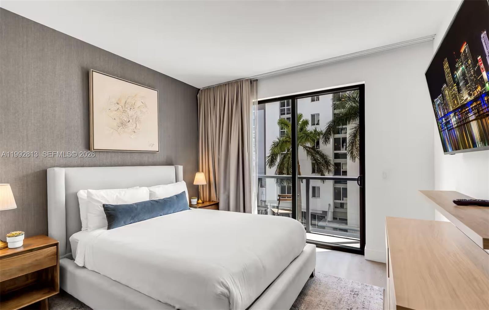 A bedroom features a white upholstered bed, a gray accent wall, and a balcony door — 229 SW 9th St # 202, Miami FL 33130, MIAMI, FL
