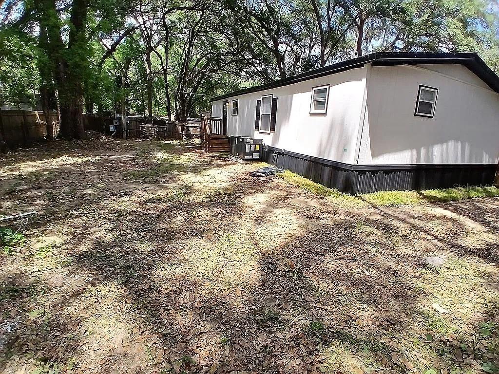 A side view of a manufactured home with a wooden deck and a dirt yard — 6626 NW 60 CT #9, OCALA, FL