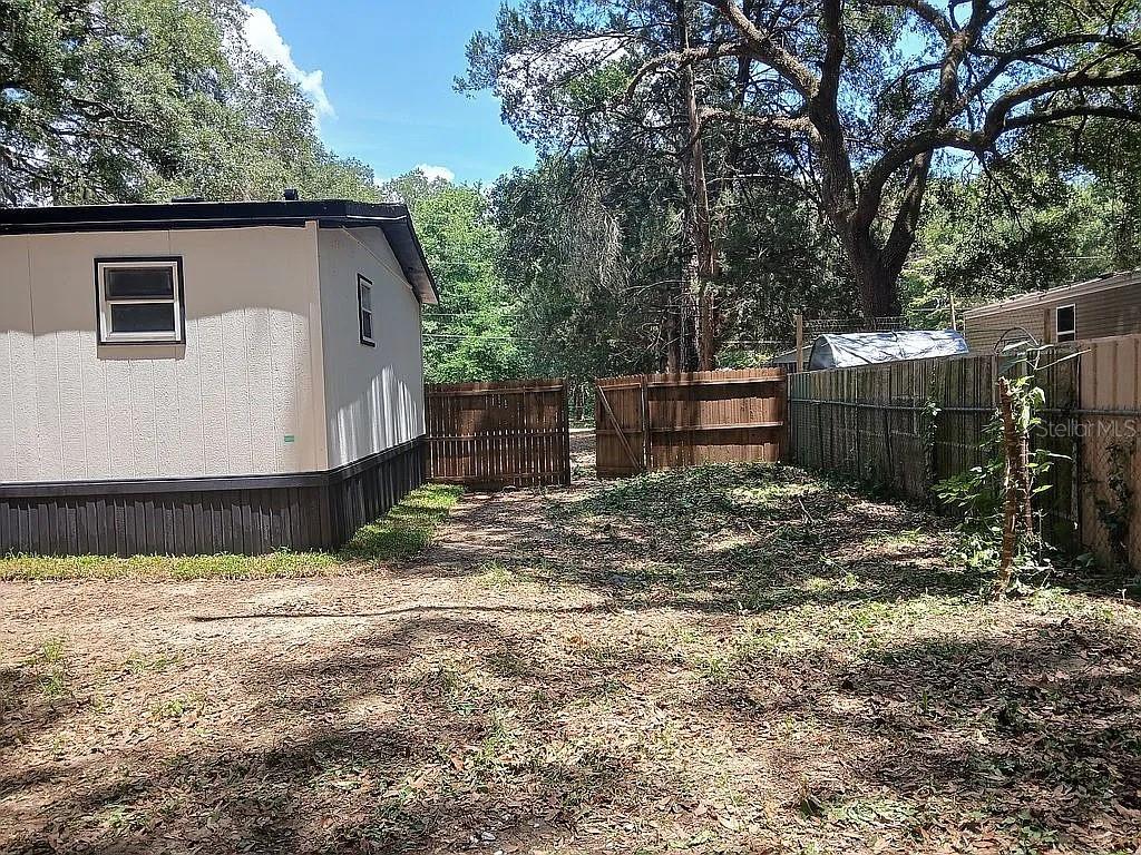 The exterior of a mobile home features a wooden fence and a dirt yard — 6626 NW 60 CT #9, OCALA, FL