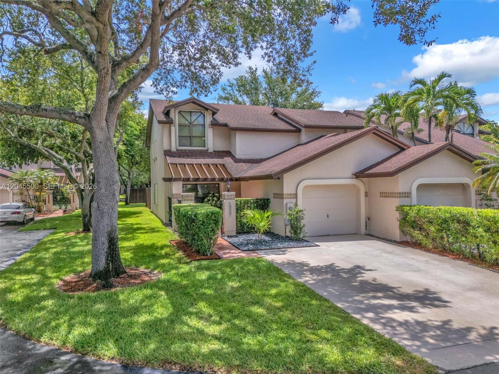 A two-story townhouse with a beige stucco exterior, brown roof, and a single-car garage — 10060 SW 137th Ct, Miami FL 33186, MIAMI, FL