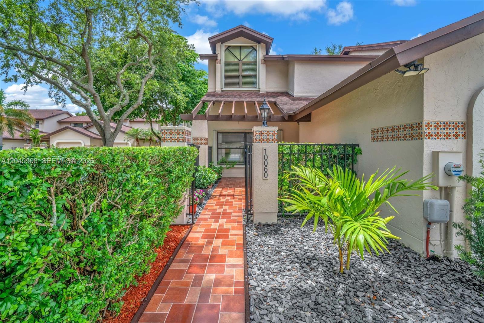 A tiled walkway leads through a gate to the entrance of a two-story stucco home — 10060 SW 137th Ct, Miami FL 33186, MIAMI, FL