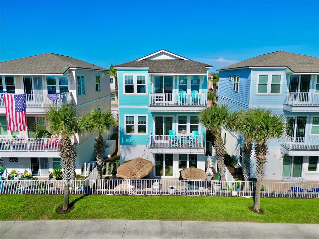 An exterior view of a three-story teal house with balconies and a fenced backyard — 2718 SUNSET INLET DRIVE, FLAGLER BEACH, FL