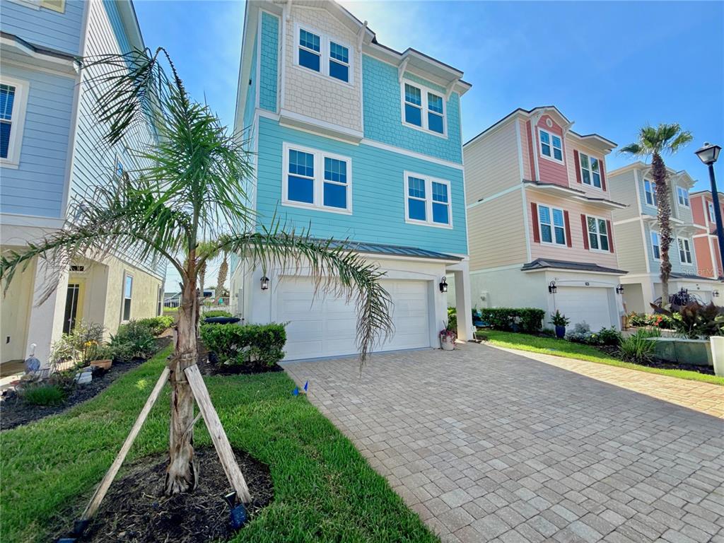 A three-story blue house with a two-car garage and a paved driveway — 2718 SUNSET INLET DRIVE, FLAGLER BEACH, FL