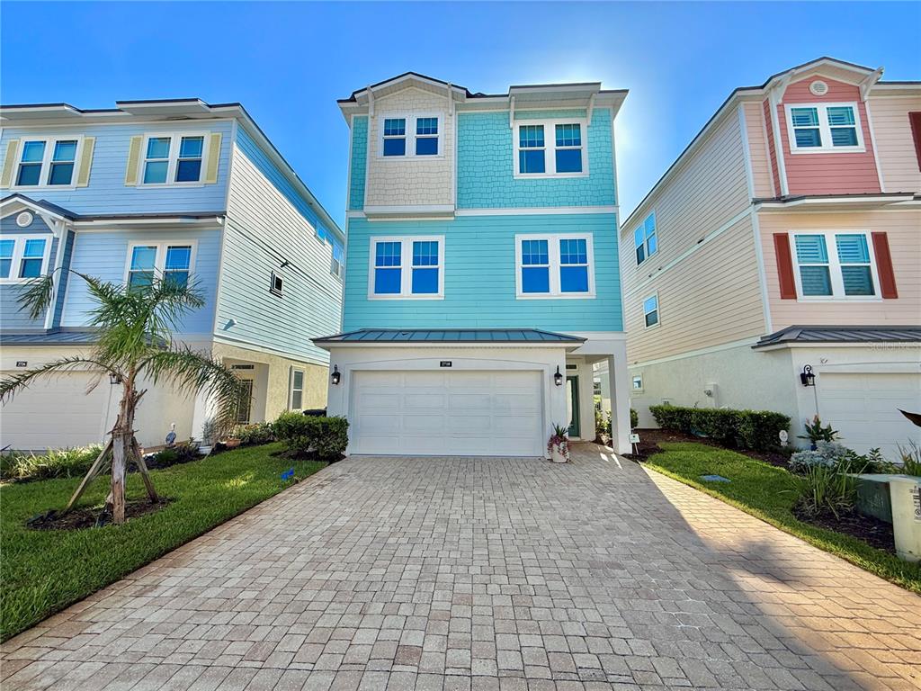 A three-story house with blue siding and a paved driveway sits between two neighboring homes — 2718 SUNSET INLET DRIVE, FLAGLER BEACH, FL
