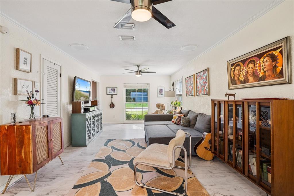 A living room features a gray sectional sofa, a patterned area rug, and wood cabinetry — 2464 LYDIA WAY, NEW SMYRNA BEACH, FL