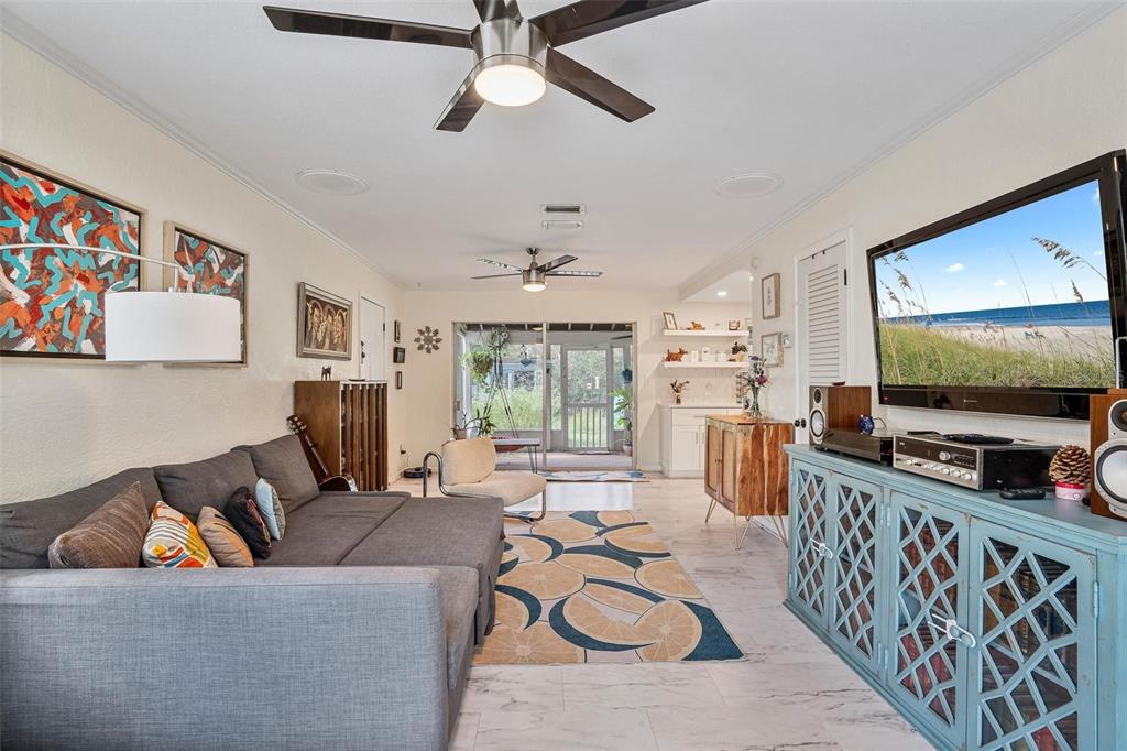 A living room features a gray sectional sofa, a blue media console, and a ceiling fan — 2464 LYDIA WAY, NEW SMYRNA BEACH, FL