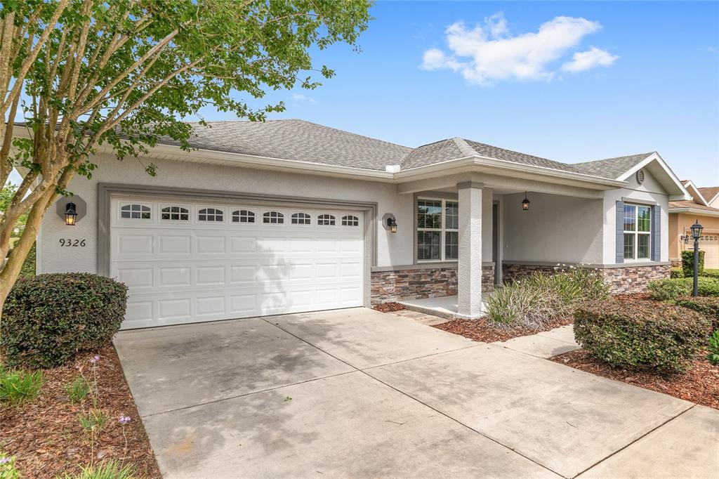 A single-story house with a white garage, stone accents, and a covered front porch — 9326 SW 97TH CIRCLE, OCALA, FL