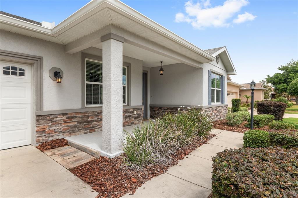 A house exterior features a covered porch, stone veneer siding, and a concrete walkway — 9326 SW 97TH CIRCLE, OCALA, FL